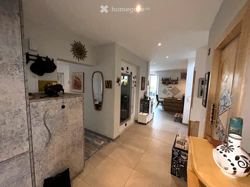 white wall, white tile floor, round mirror, desk with chair, framed picture, vase