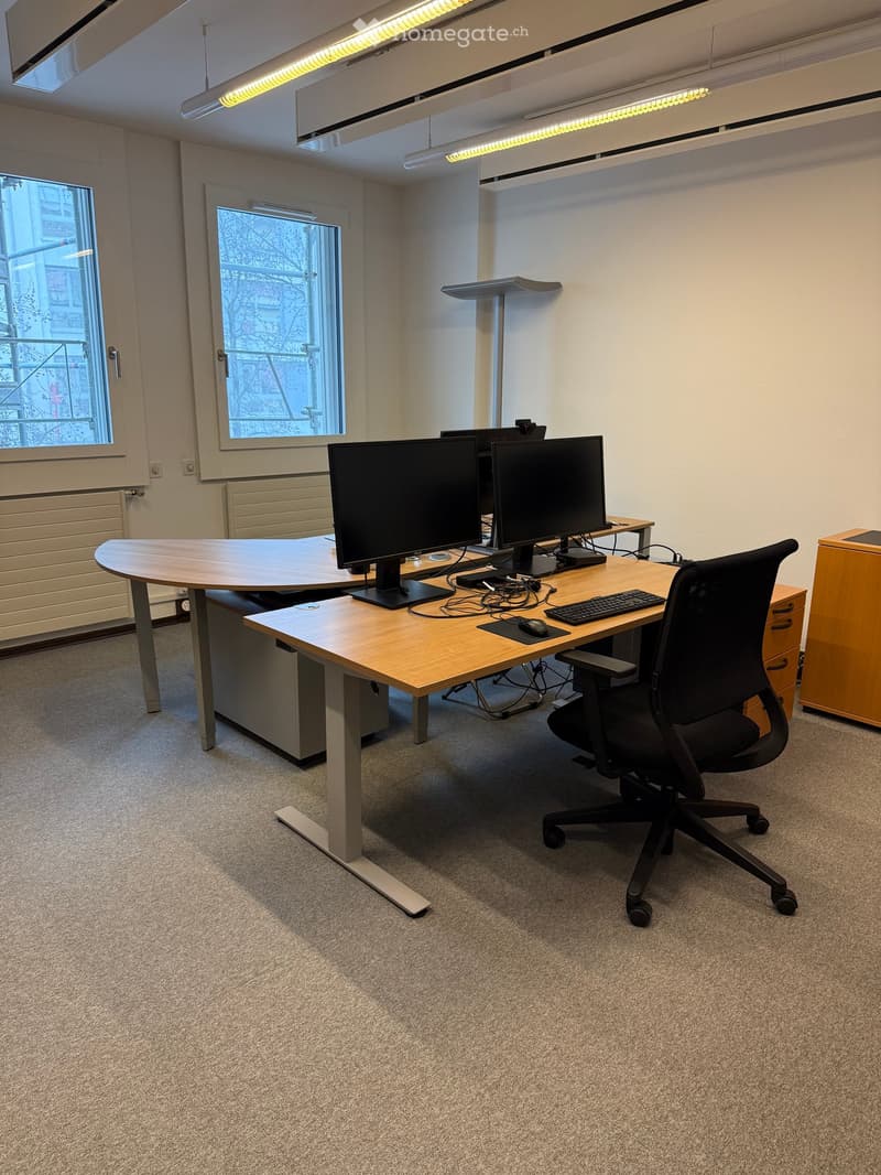 Office room with a desk, chair, monitors, cabinets, and a power outlet.