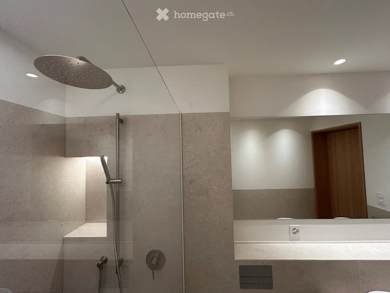Modern shower, white tile walls, glass partition, built-in shelf, mirror, power outlets, silver hardware