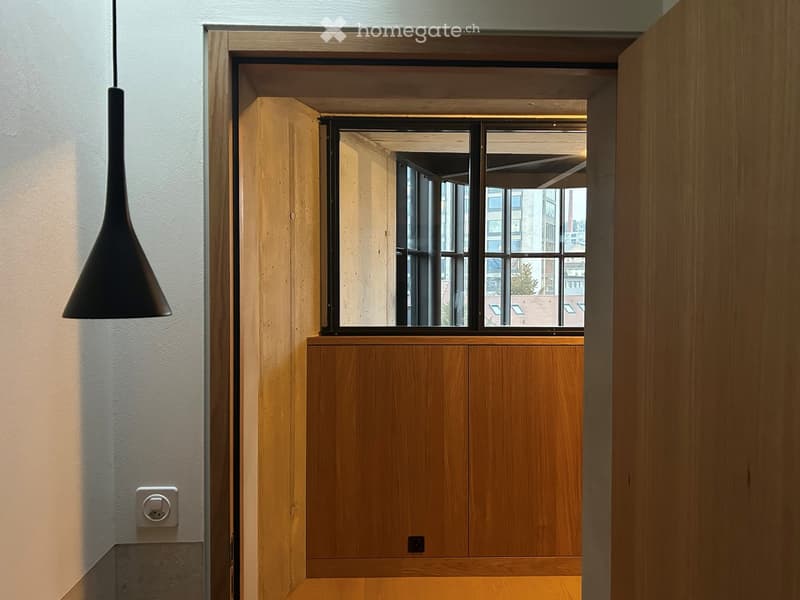 open doorway, natural light, wooden door, exposed floor beam, large window, view of the outside