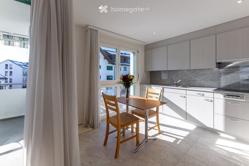 white cupboards, granite countertops, wooden table, chairs, flowers, balcony with view
