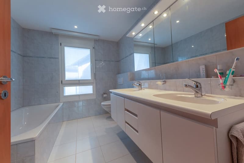 white bathtub, two sinks, mirror, large window, tiled floors
