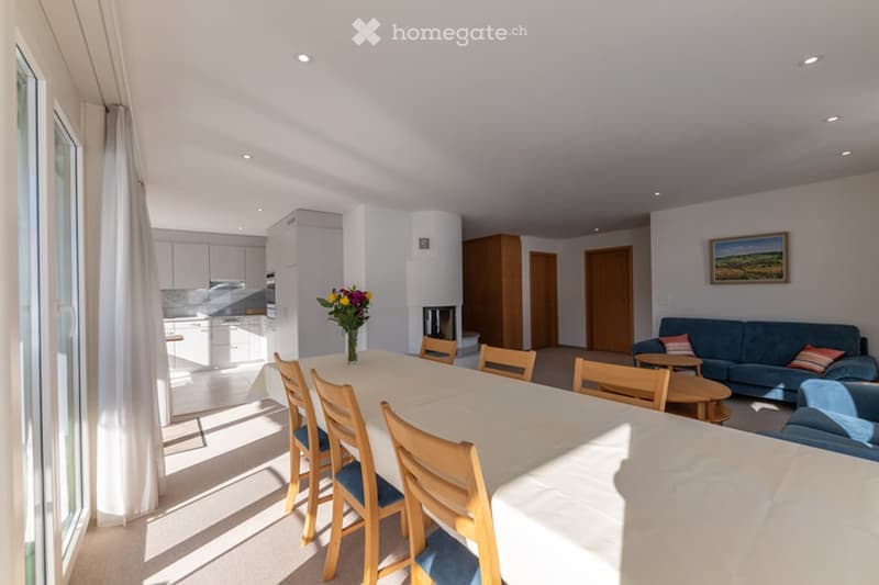 long dining table, wooden chairs, decorative flowers, fireplace, white and blue couch