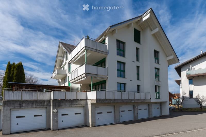 white building with green accents, multiple floors, multiple garages, balconies