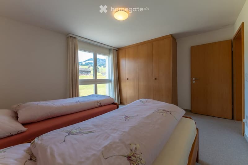 Bedroom with two single beds, white bedding with floral design, wooden wardrobe, window with countryside view, single white pillow on each bed