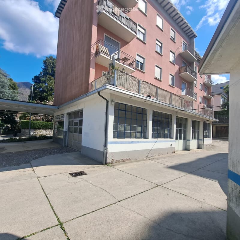 3 story building, pink exterior, white ground floor, garage, balconies, windows