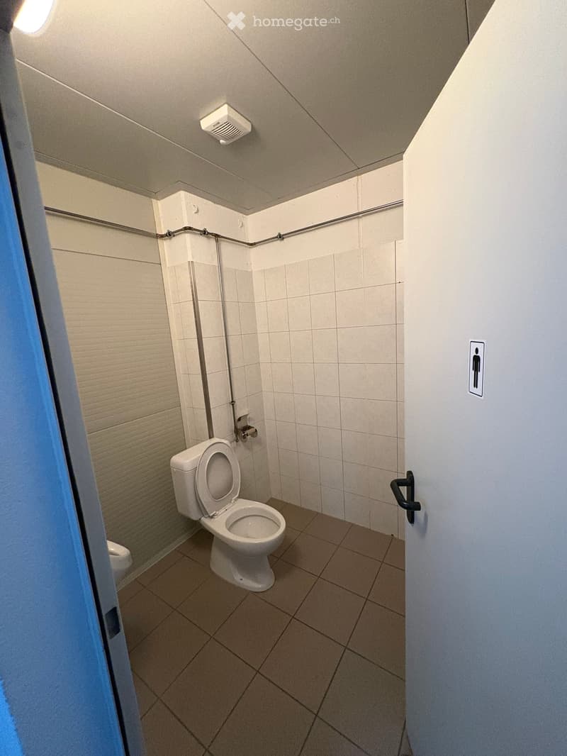 A small bathroom with a toilet, a sink, and tiled walls and floor.