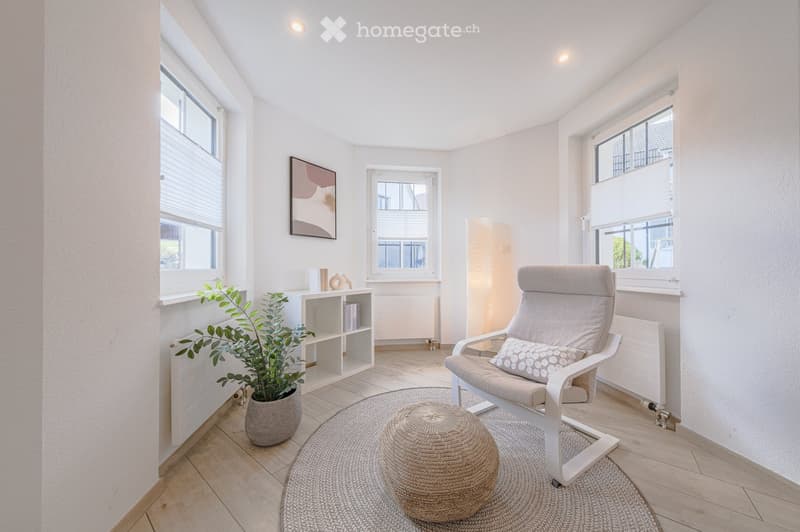 white walls, wooden floor, white chair, round rug, potted plant, white shelves, picture frame, windows with blinds
