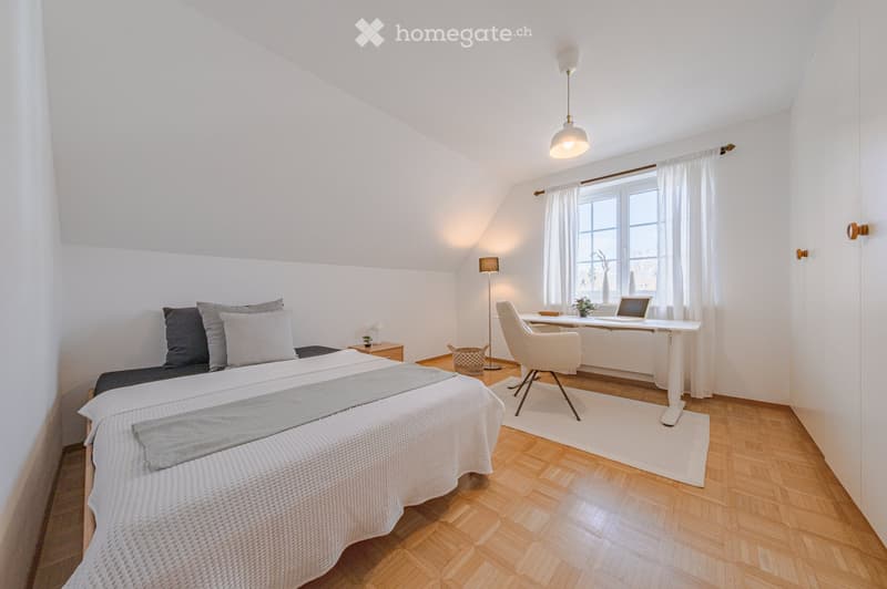 Bedroom with bed, desk, chair, lamp, window, rug, and plants