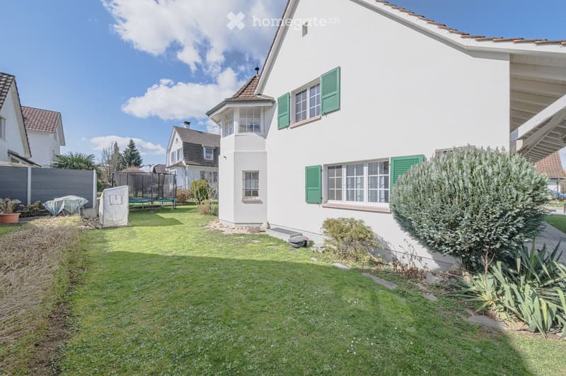White house with green shutters, large garden, trampoline, and a small shed