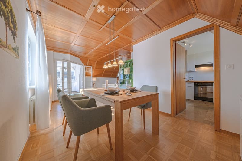 Dining room with wooden table, chairs, wooden ceiling, white walls, open door to kitchen