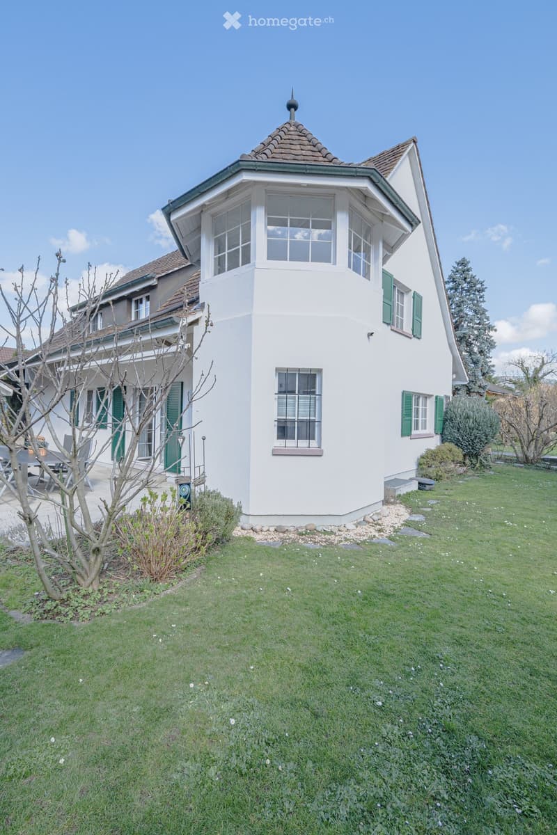 white house, green shutters, brown roof, large windows, garden, outdoor seating area
