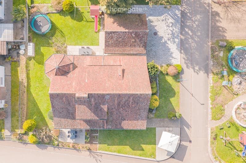 2 story house, red brick roof, driveway, garden, trampoline, slide