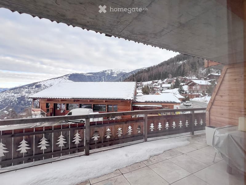 balcony with wooden railing, snow-covered mountains, wooden house, table with cover