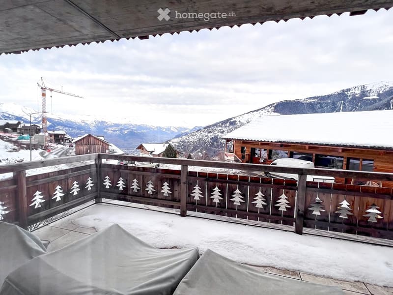 wooden railing, covered chairs, snowy mountains in the background
