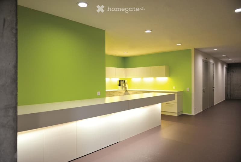 modern kitchen with green walls, white cabinets, countertops, and lighting