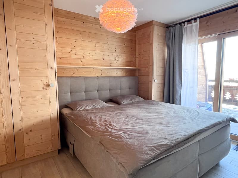 wooden walls, wooden floor, double bed, two pillows, wooden wardrobe, lamp, sliding glass door