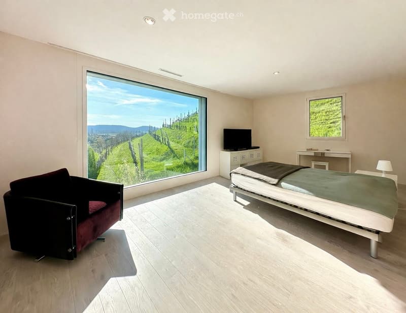 modern room with large window, bed, chair, desk, television, lamp