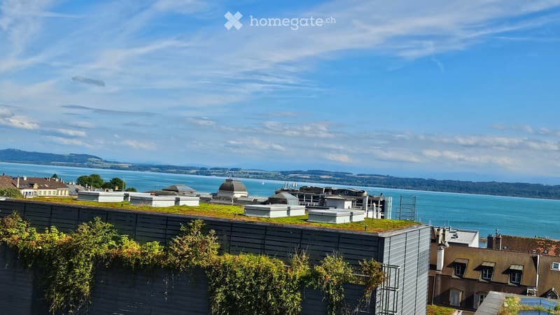 Building with green roof, overlooking a large body of water and mountains