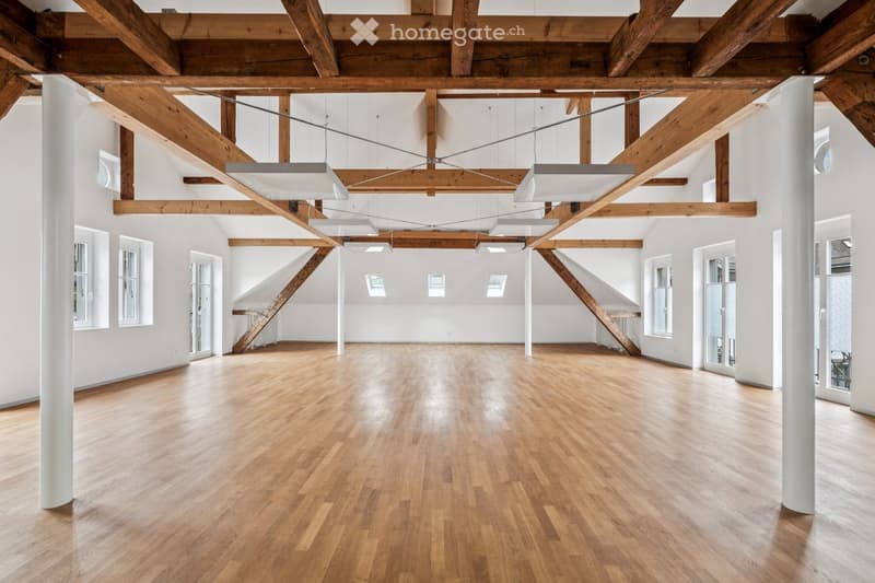 large open space, wooden floor, wooden beams, white walls, large windows, skylights