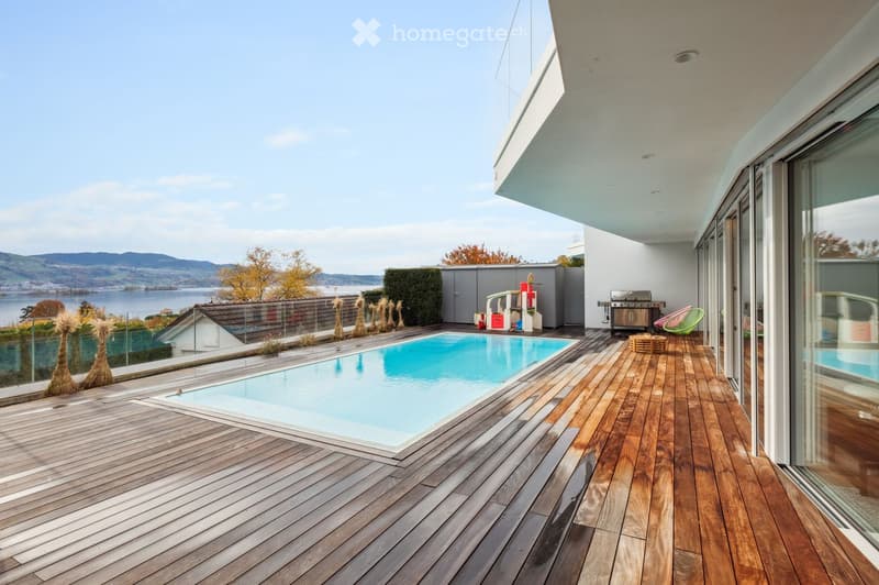 Modern house with wooden deck, swimming pool, glass railings, lake view