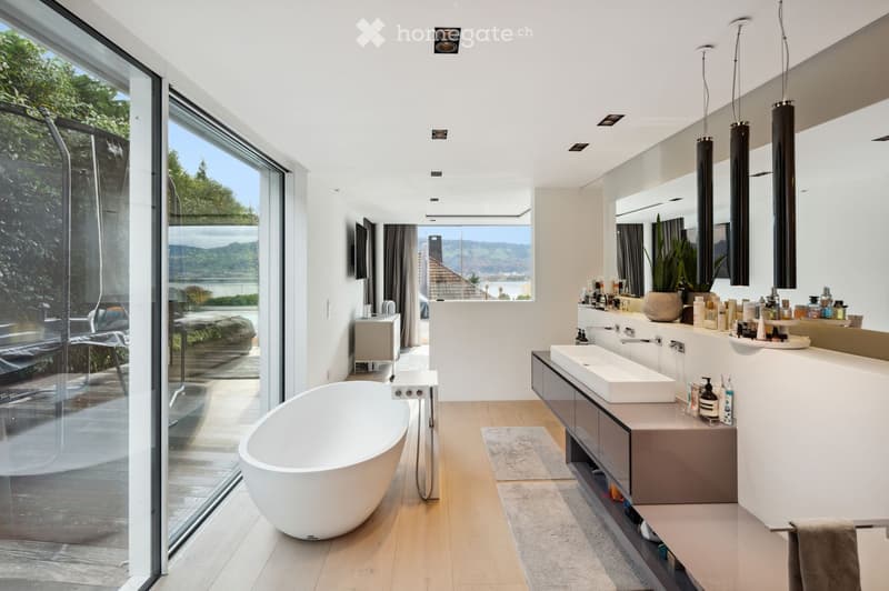 modern bathroom with large windows, bathtub, double sink, large mirror, wooden floor, plants