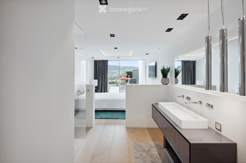 modern bathroom with white walls, wooden floor, large mirror, double sink, large window, bedroom visible