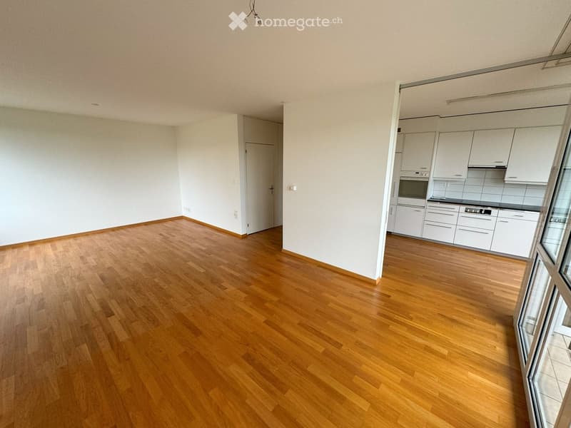 empty room with wooden floor, sliding doors, white kitchen cabinets