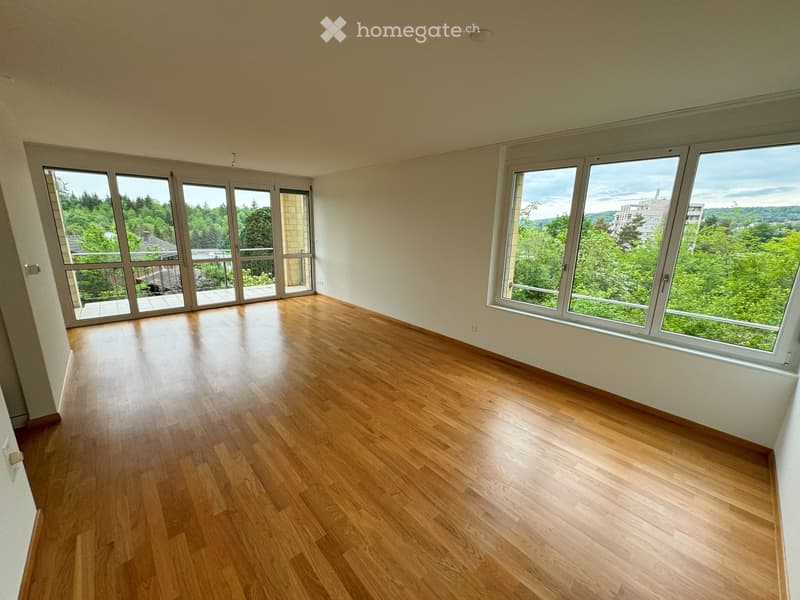 Hardwood floors, sliding glass doors to a balcony, large windows with view to the forest