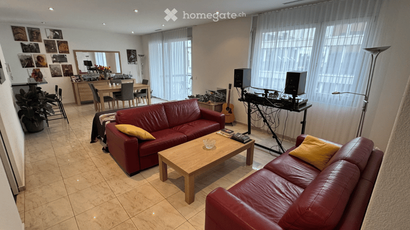Red leather couches, wooden coffee table, dining table, speakers, guitar, floor lamp, curtains