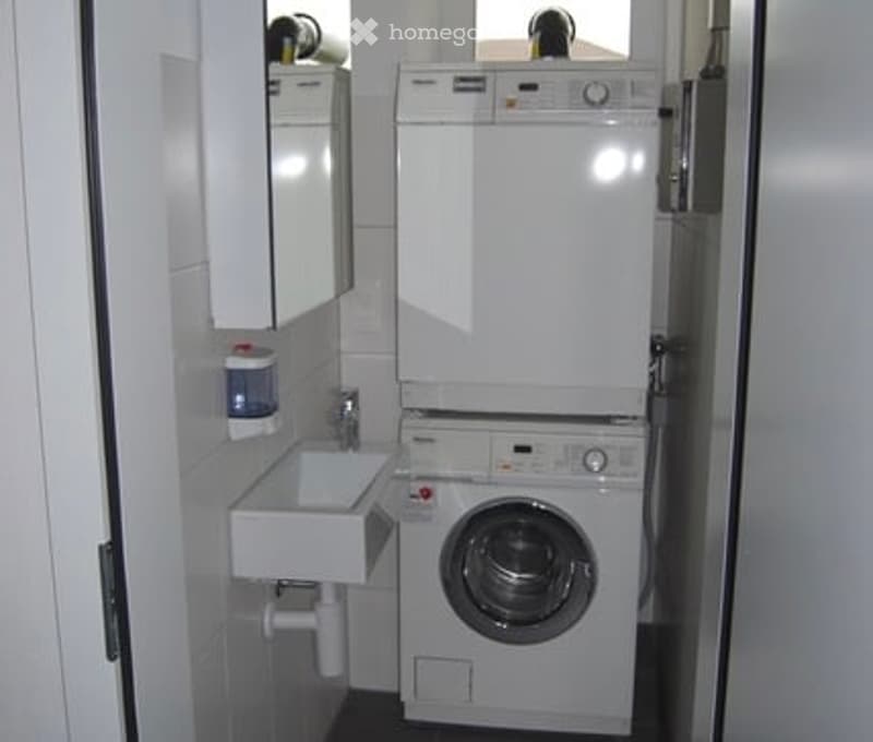 white washing machine, white sink, white tiles, mirror, dispenser