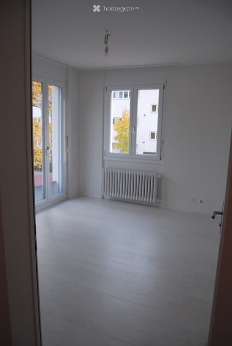 empty room, white walls, white floor, sliding glass doors, white radiator, view of trees