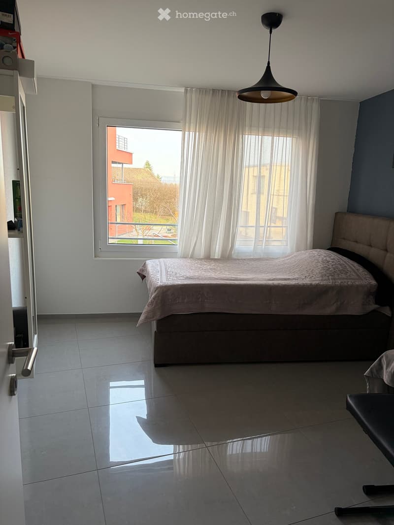 bedroom with bed, window with balcony, white walls, white tiled floor, lamp