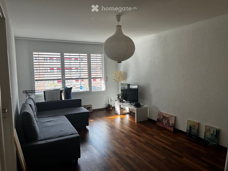 Living room with a couch, TV, and a window with blinds