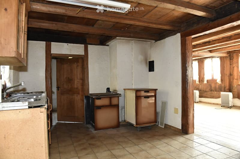 kitchen with wooden cabinets, tiled floor, wooden beams, sink, two old appliances, wooden door