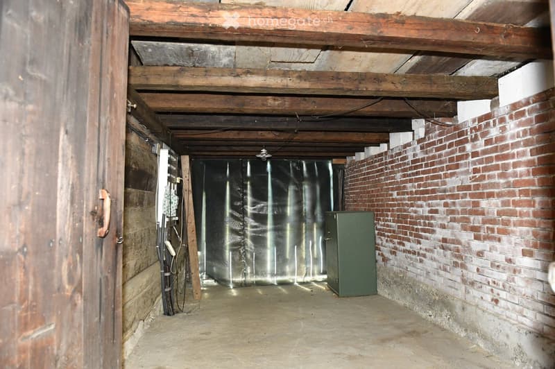 basement room, wooden beams, brick wall, green storage box, black curtain