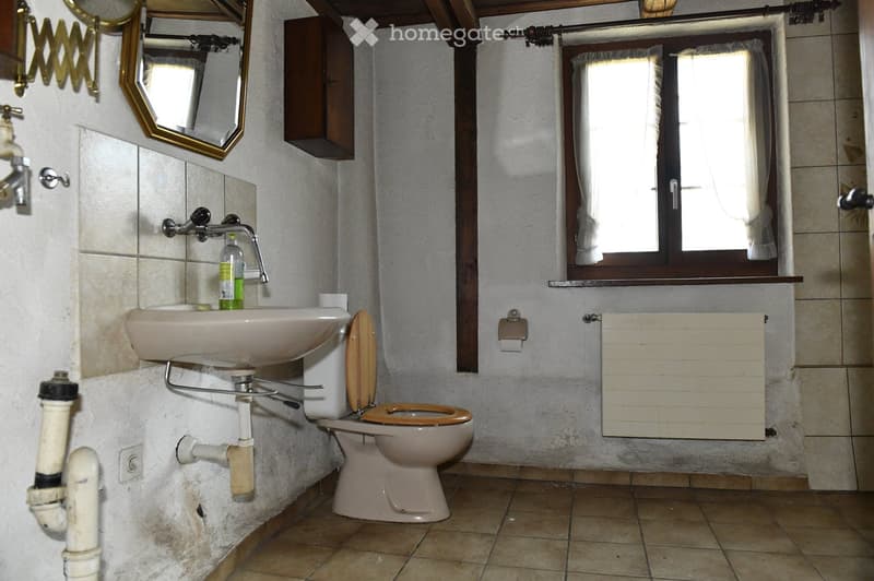 A small bathroom with a toilet, sink, and window.