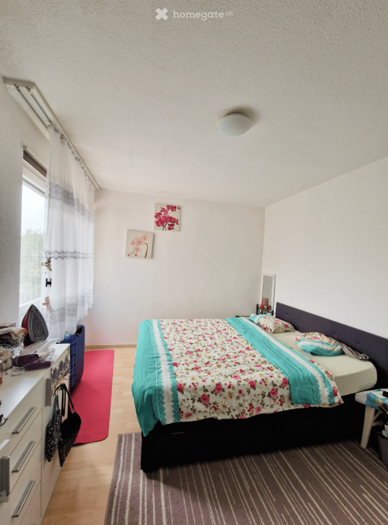 bedroom with a bed, cabinet, mirror, rug, and flowers on the wall