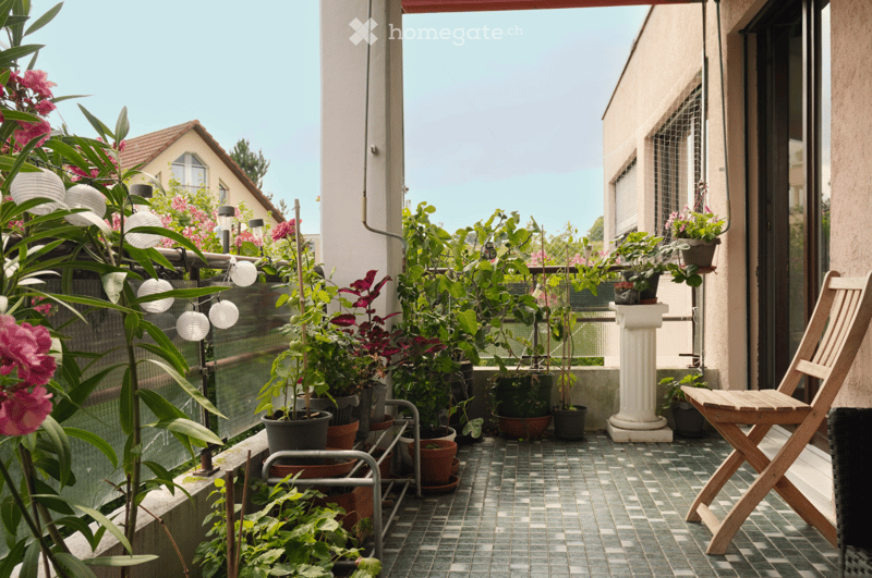 tiled floor, balcony with glass railing, wooden chair, potted plants, small column, multiple lights