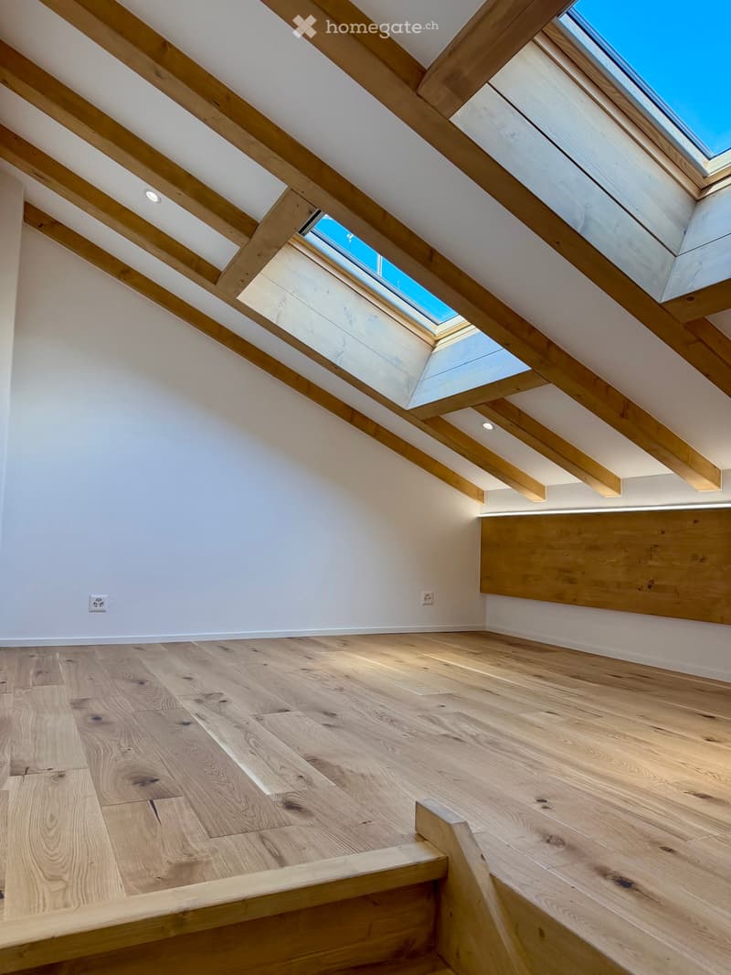 wooden floor, white walls, wooden ceiling beams, two skylights, power outlets