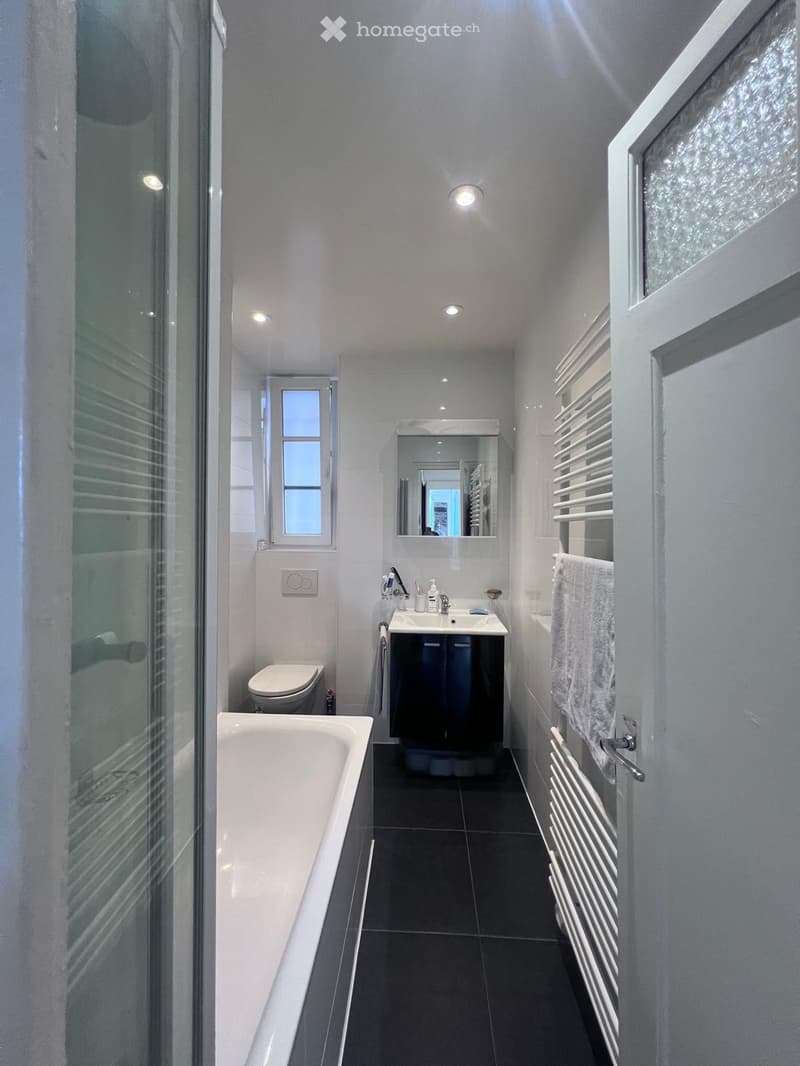 Bathroom with bathtub, sink, toilet, mirror, and towel rack
