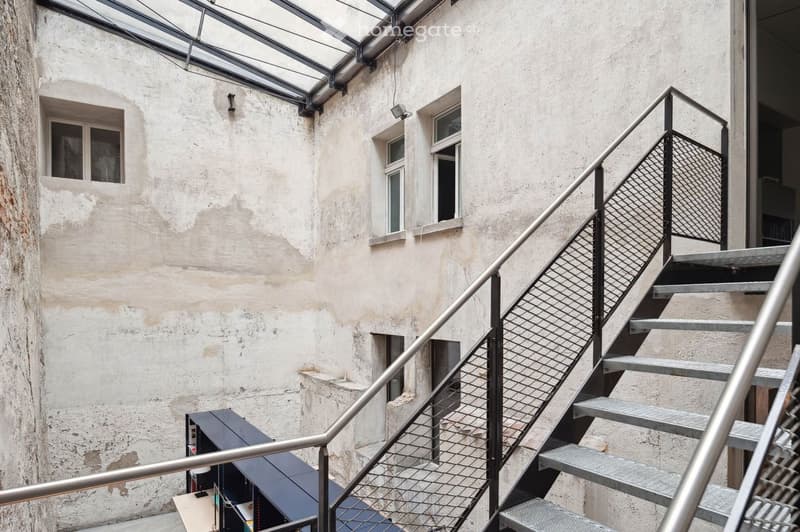 Old building, metal railing, glass roof, visible brick walls, stairs leading down