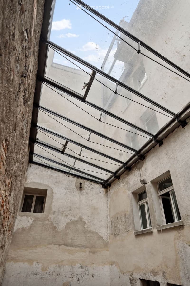 Courtyard with a glass roof, multiple windows on three walls, brick wall on one side