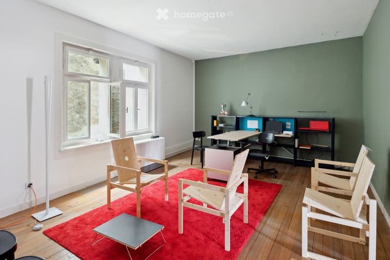 room with white and green walls, red carpet, wooden chairs, desk with computers, white lamp