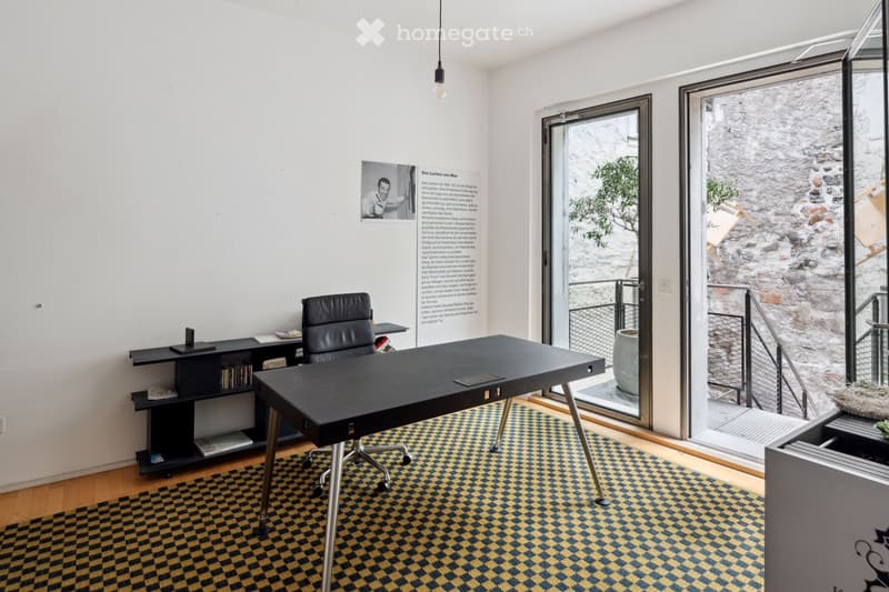 Office with desk, chair, cabinet, rug, glass doors, and balcony