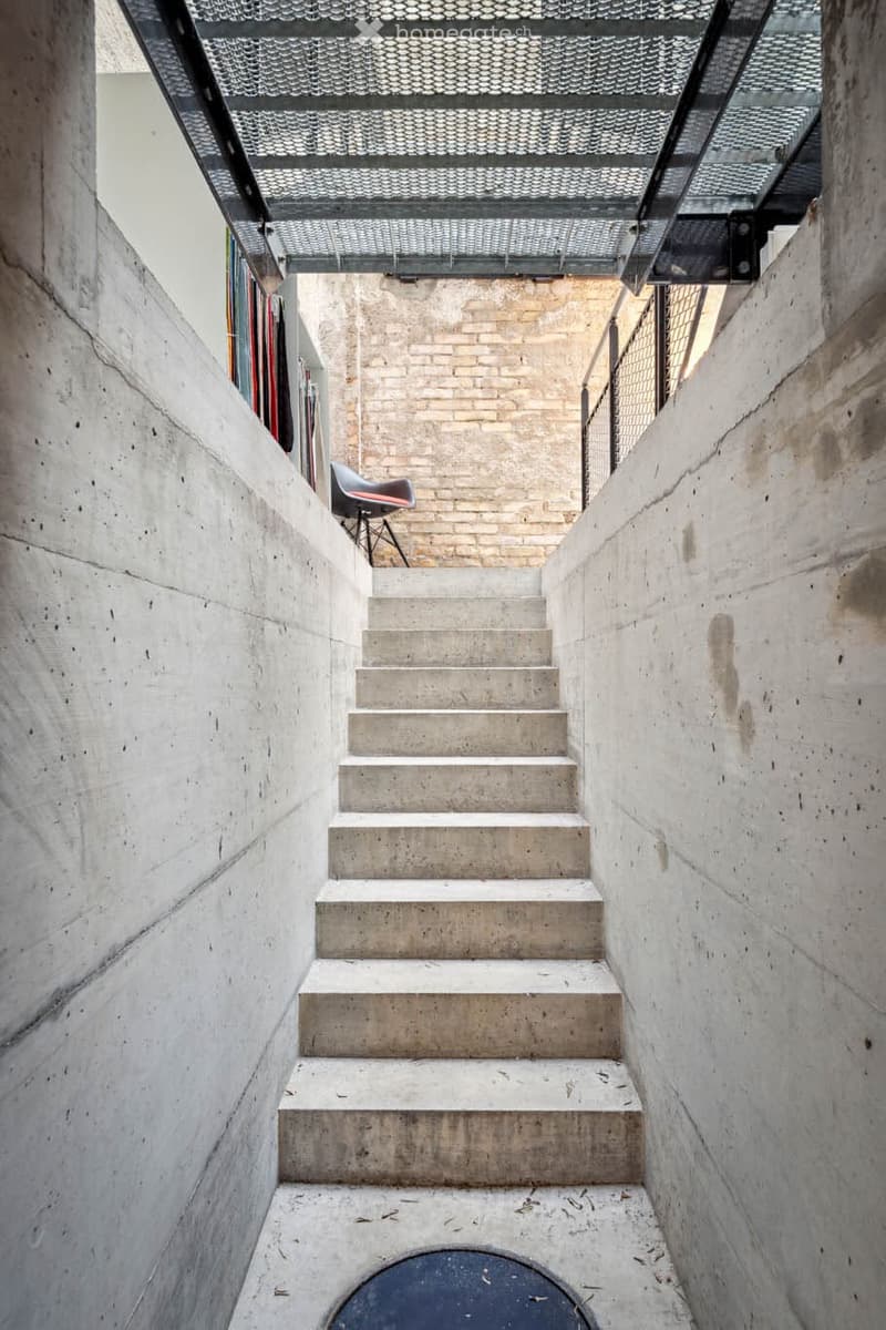 Concrete staircase with a spiral design, white and gray cement finish, industrial style, steel grate at the top