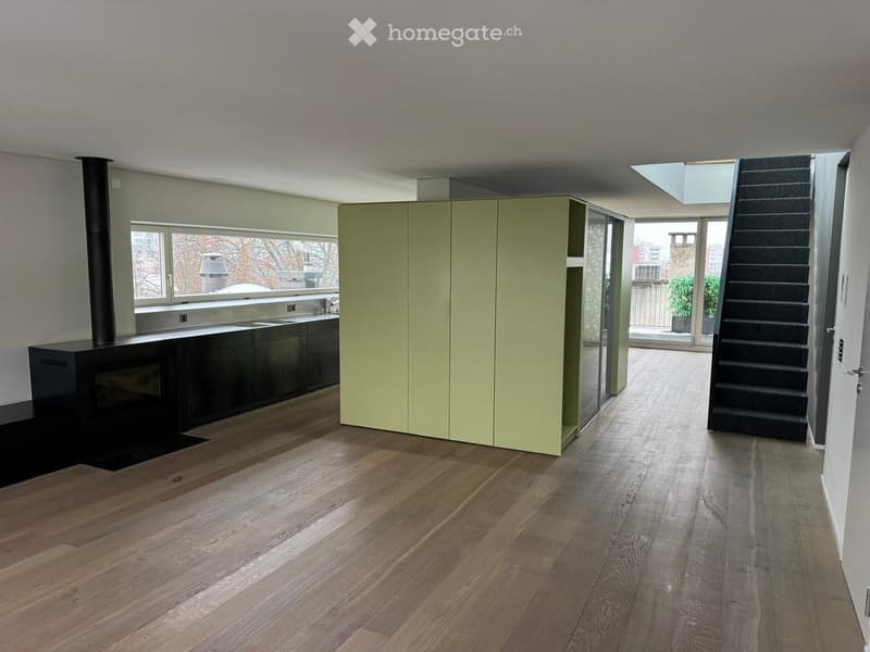 Open space with wooden floor, green cabinets, black fireplace, staircase, large window