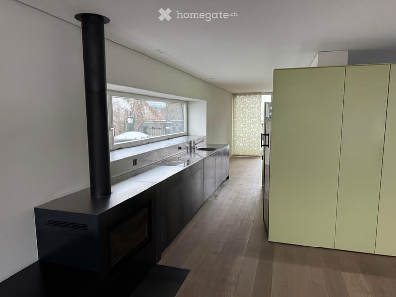 modern kitchen with stainless steel countertops, black fireplace, large window, wooden floor