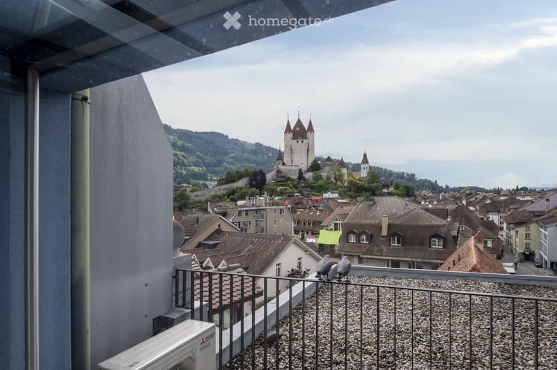 view from an upper-level balcony of a cityscape with a castle in the background