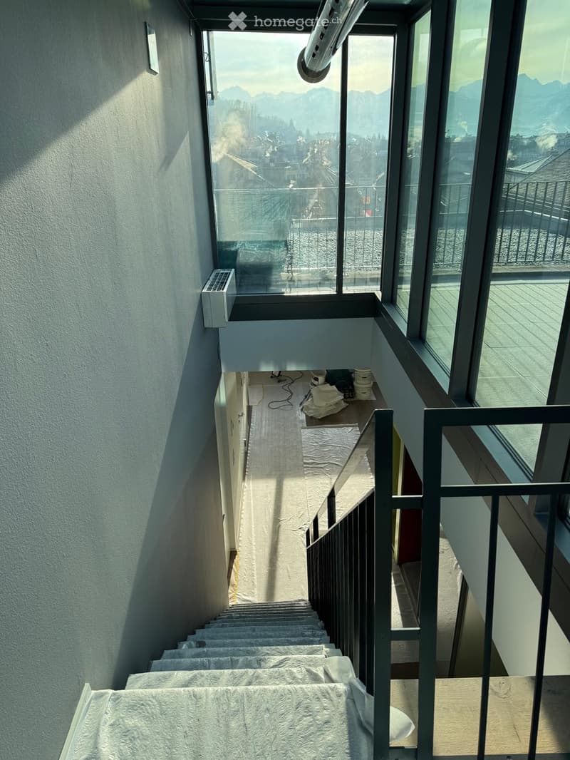 Staircase with covered steps, large windows, balcony, view of the mountains